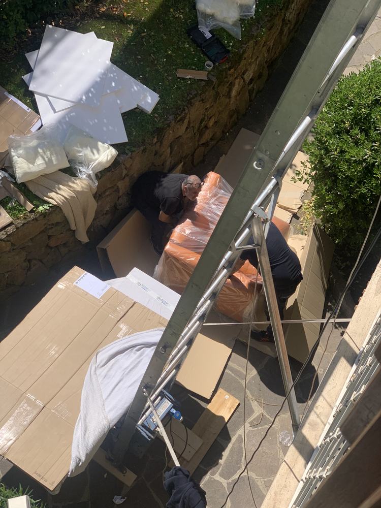 Operatori di M&M Global Services imballano un divano accanto alla scala aerea durante un trasloco a Roma